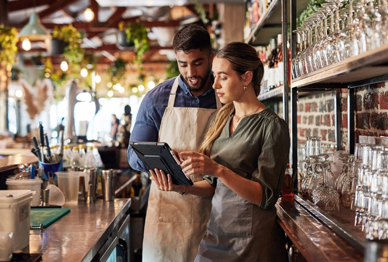 two shop workers looking at a tablet