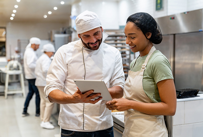 chef and kitchen employee looking at tablet together